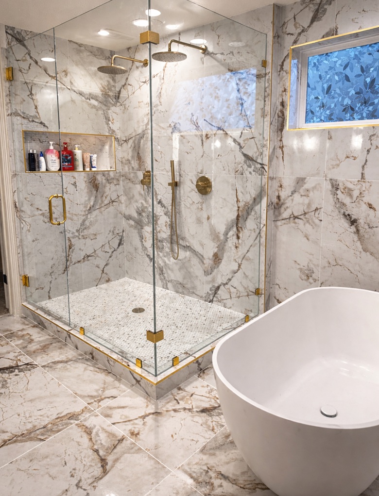 Expanded walk-in shower with dual rain heads, marble-look porcelain tile, built-in niche and freestanding tub in an Edina primary bathroom remodel